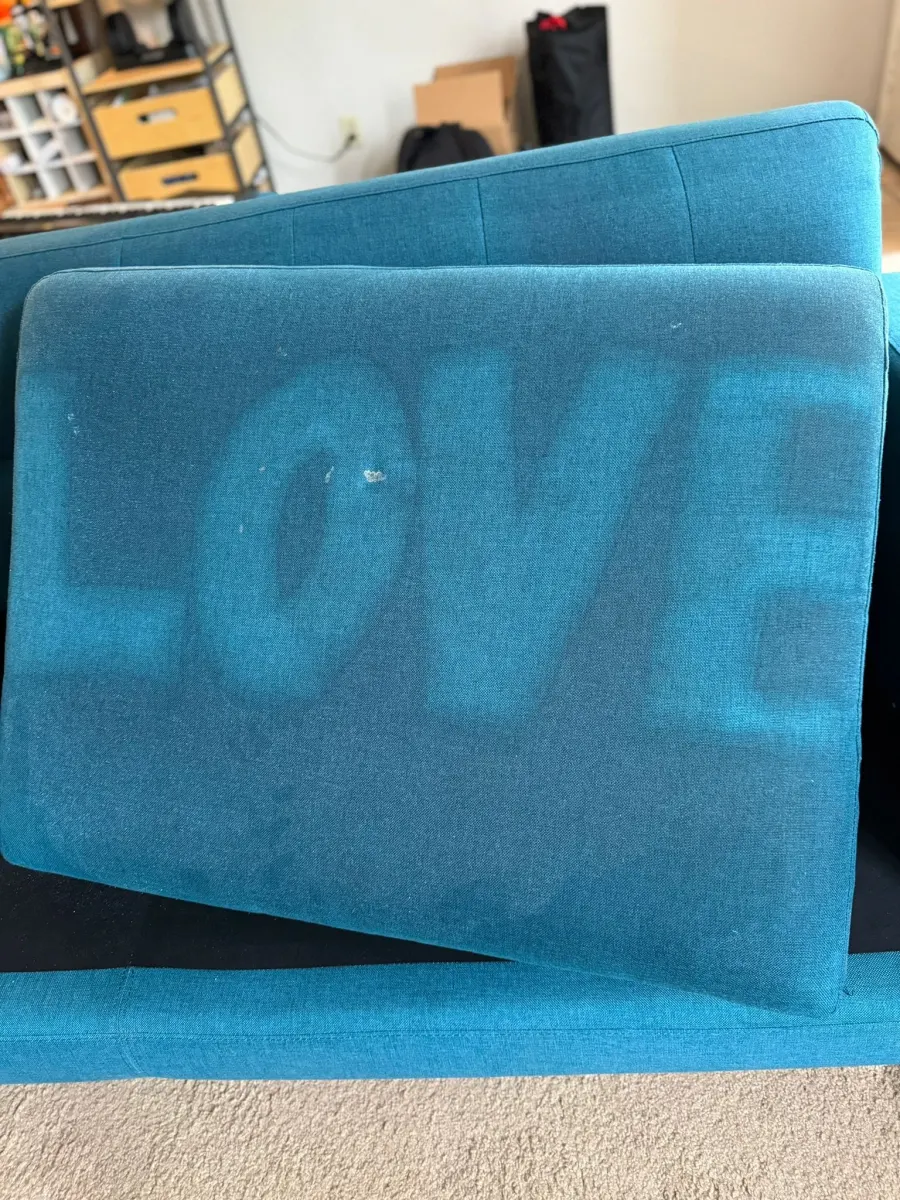“LOVE” cleaned into a teal sofa cushion
