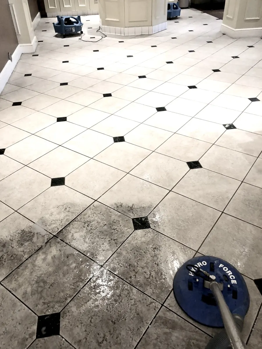 Spinner tool cleaning a white tile floor, cleaned vs. uncleaned area